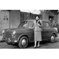 Una ragazza posa insieme ad una Fiat 1100 davanti ad una delle porte d'ingresso delle casermette di Borgo San Paolo, Torino, 1954